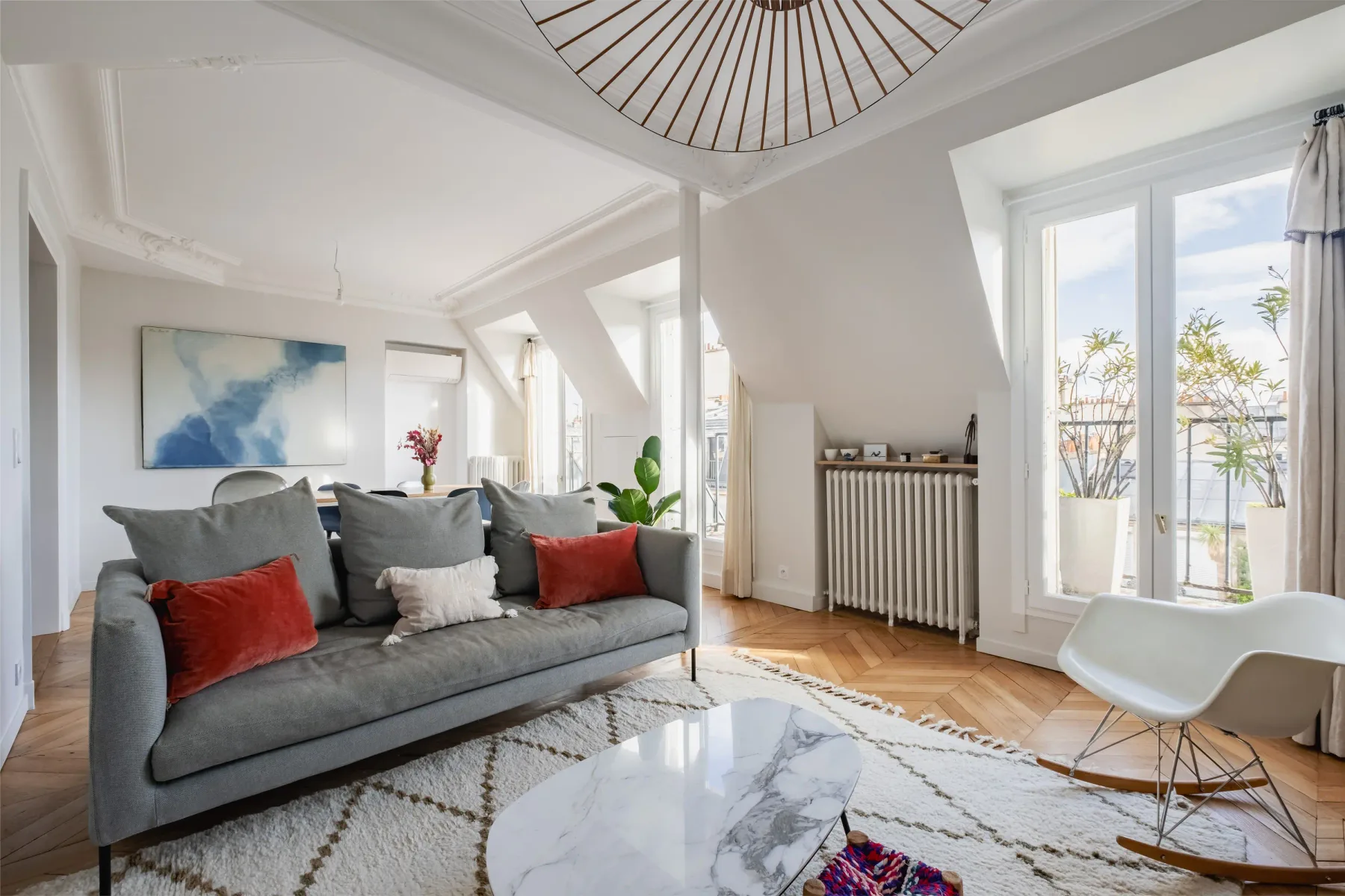 A bright living room with gray seating and large windows.