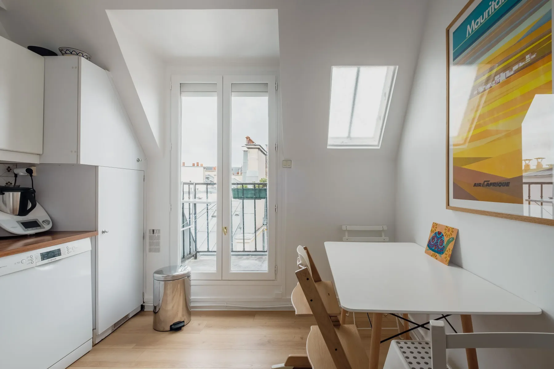A bright kitchen and dining area with a table beside the balcony doors.
