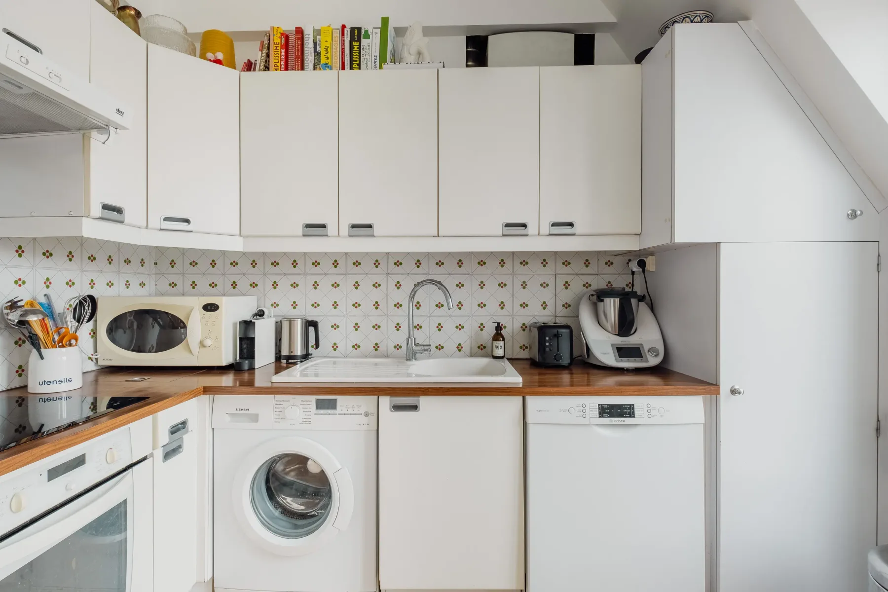 A bright kitchen with white cabinets and appliances along the counters.