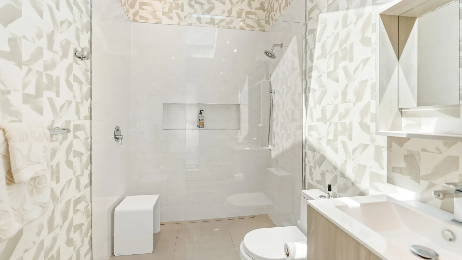 Un baño luminoso con ducha de vidrio, bañera, inodoro y lavabo.