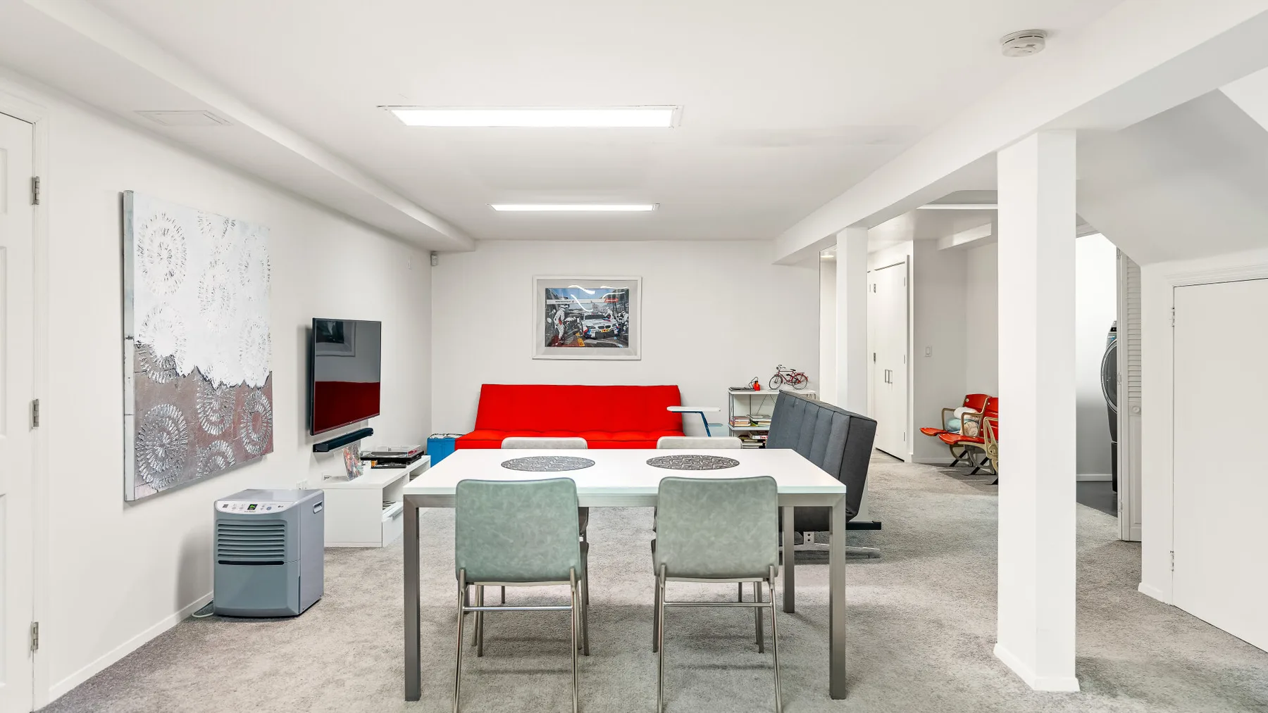 Una sala común luminosa con un sofá rojo, una mesa y asientos.