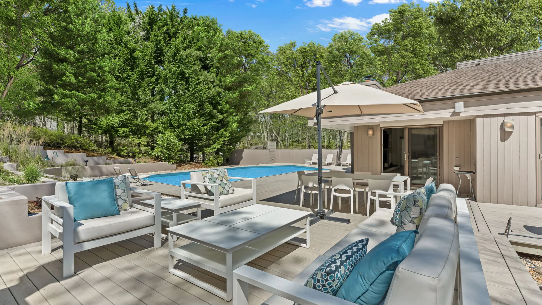Una terraza exterior con asientos y una piscina junto a una casa.