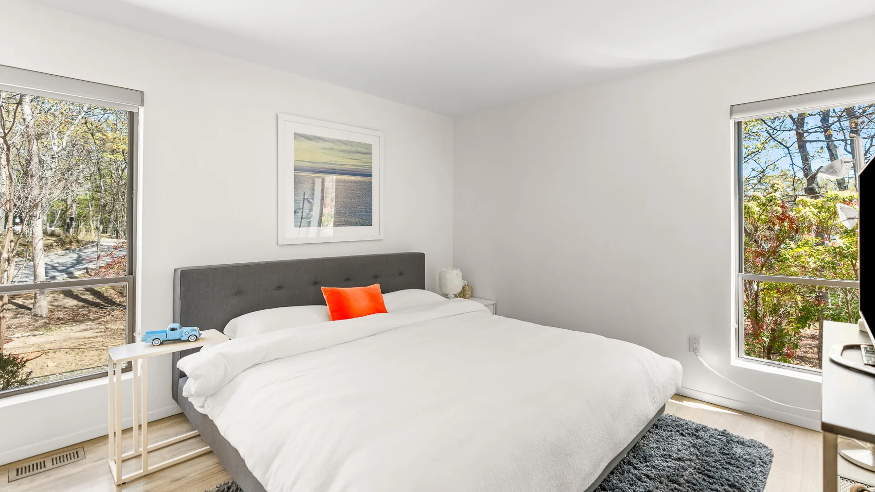 Un dormitorio luminoso con una cama grande entre dos ventanas.