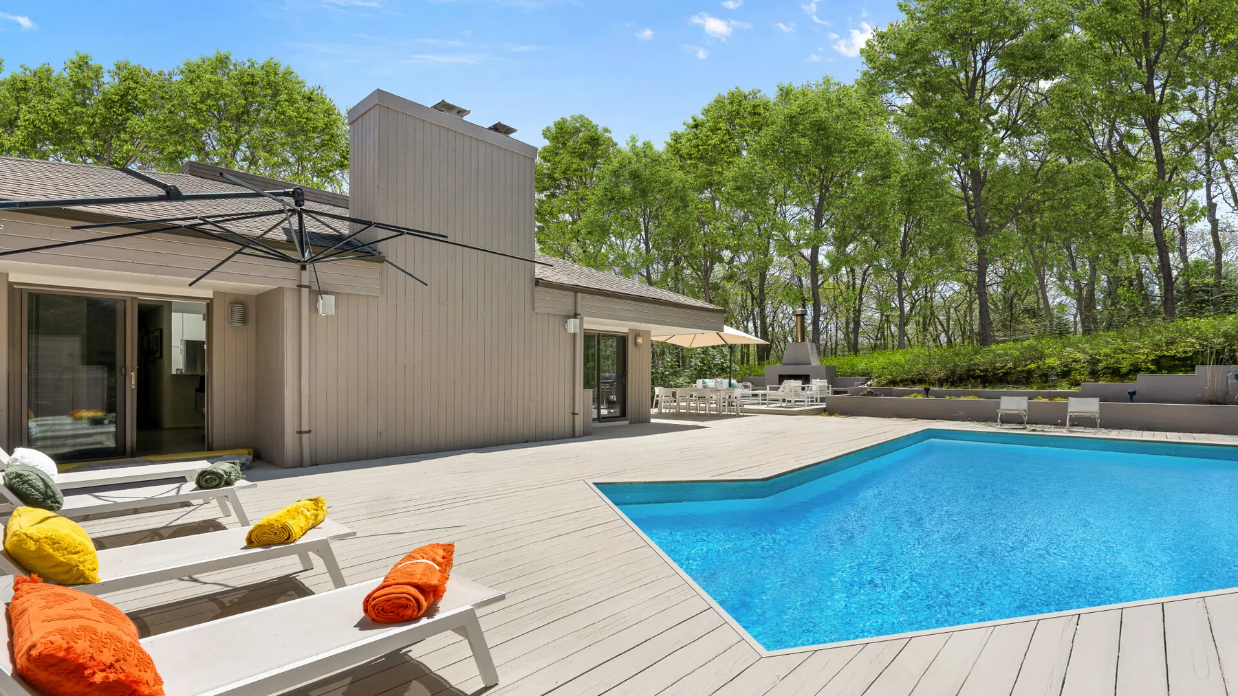 Una piscina al aire libre junto a una amplia terraza con asientos.