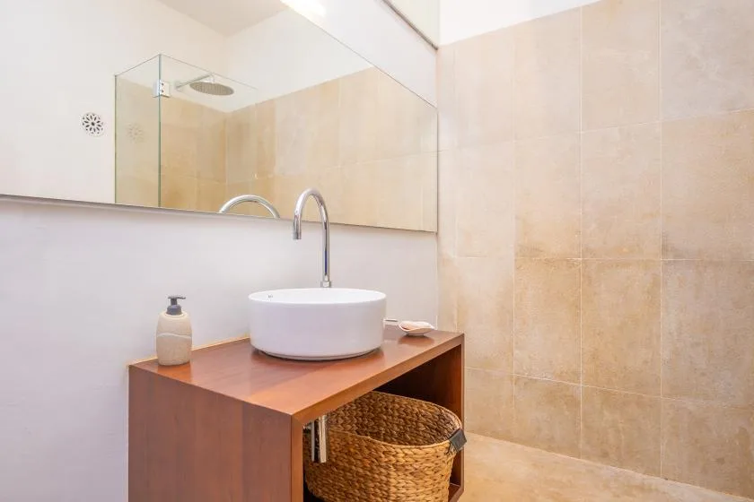Un mueble de baño con lavabo de sobreponer está junto a una ducha alicatada.