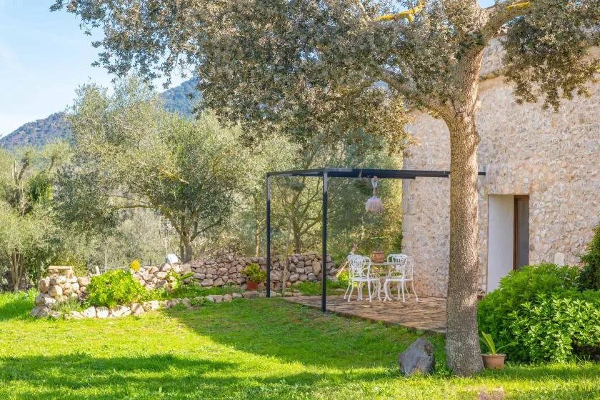 Un patio ajardinado con una mesa y sillas está junto a un edificio de piedra.