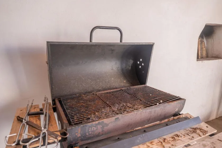 Una parrilla metálica abierta con rejillas está junto a una pared clara.