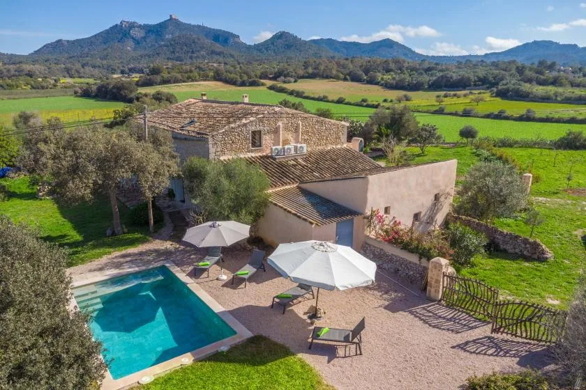 Una casa rural con piscina y patio tiene vistas a campos verdes y colinas lejanas.