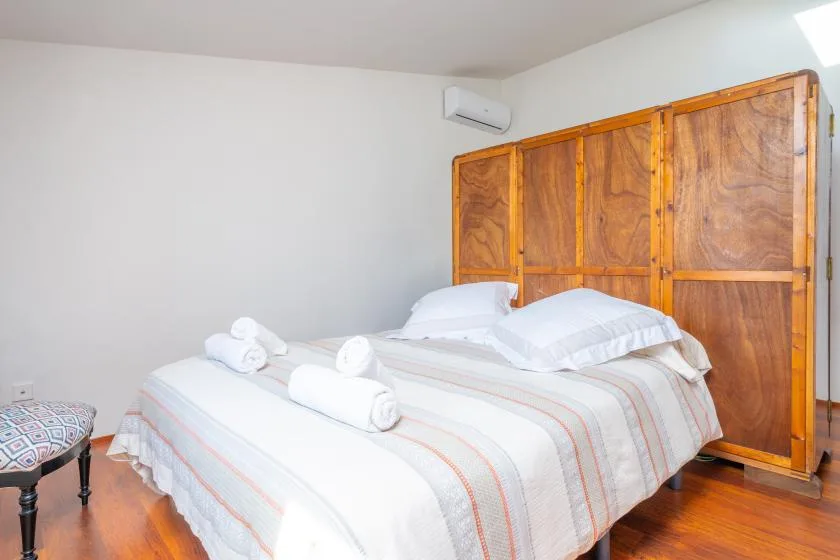 Un dormitorio con una cama bien hecha y biombos de madera.