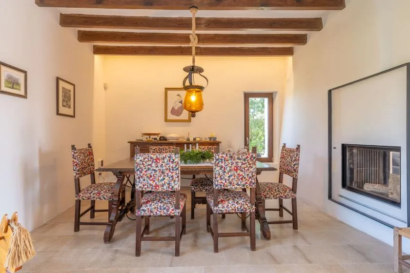 Un comedor con asientos estampados, vigas expuestas y una chimenea.