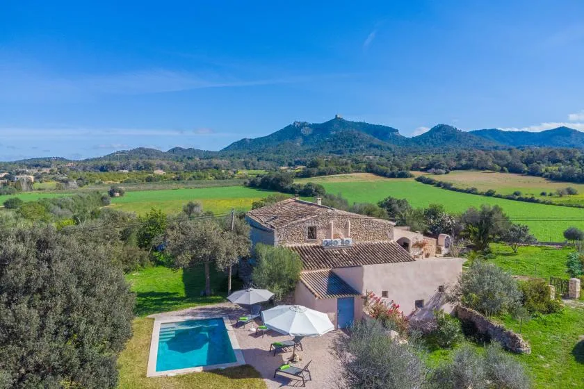 Una propiedad rural está entre campos verdes, con piscina y vistas a las montañas.