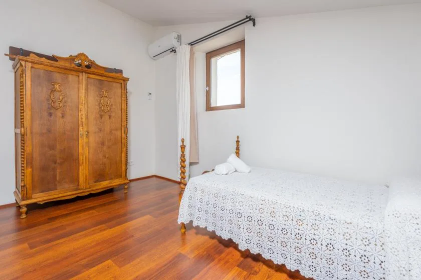 Un dormitorio con un armario de madera y una cama cubierta con una colcha blanca estampada.