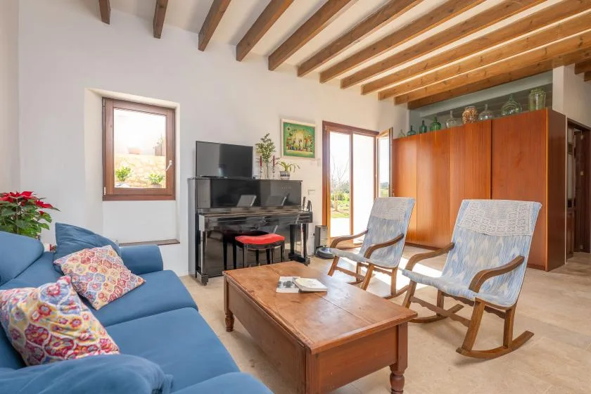 Una sala de estar con sofá azul, mesa de centro de madera y dos mecedoras.