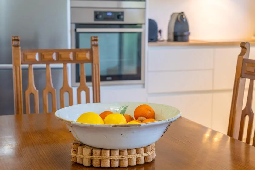 Una zona de comedor en la cocina con una mesa de madera y un cuenco de fruta.