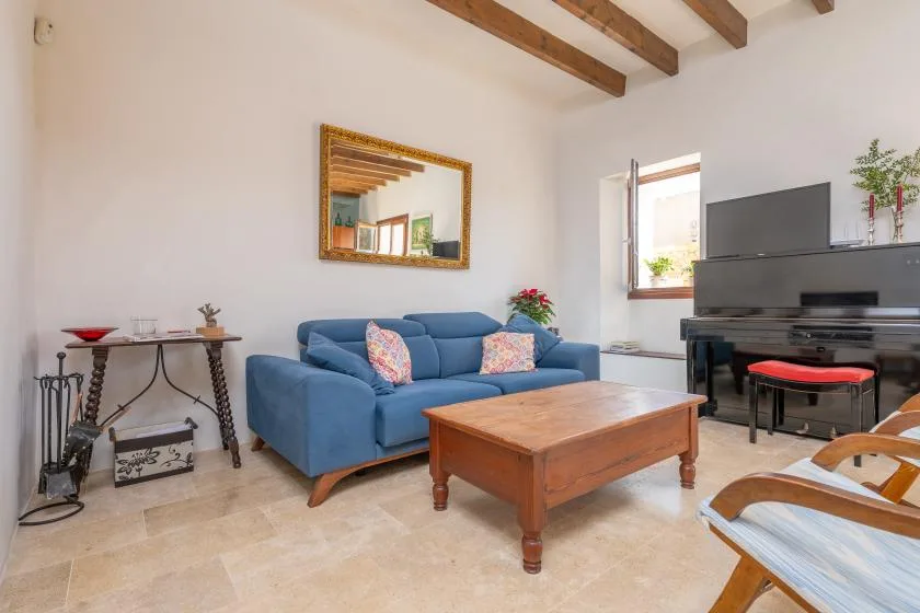 Una sala luminosa con asientos azules, una mesa de centro de madera y vigas expuestas.