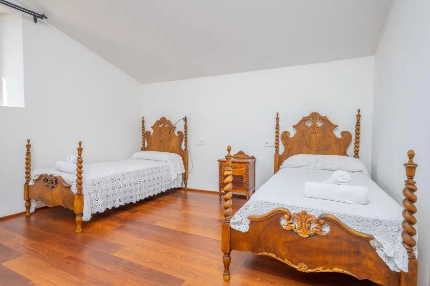 Un dormitorio con dos camas de madera tallada y una mesita de noche.