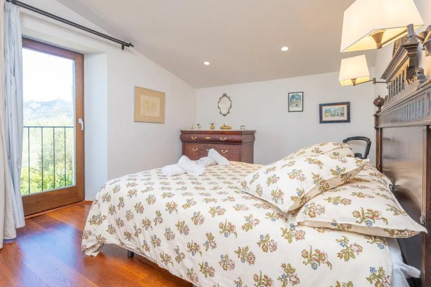 Un dormitorio con una cama de estampado floral junto a una puerta de vidrio.