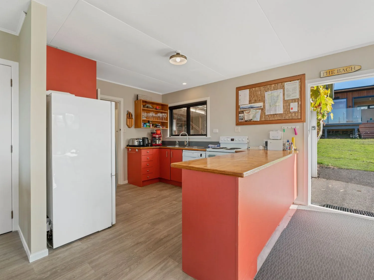 Una cocina con armarios rojos, un refrigerador blanco, una encimera de madera y una puerta que da al exterior en Henley - Omori Holiday Home, en Omori