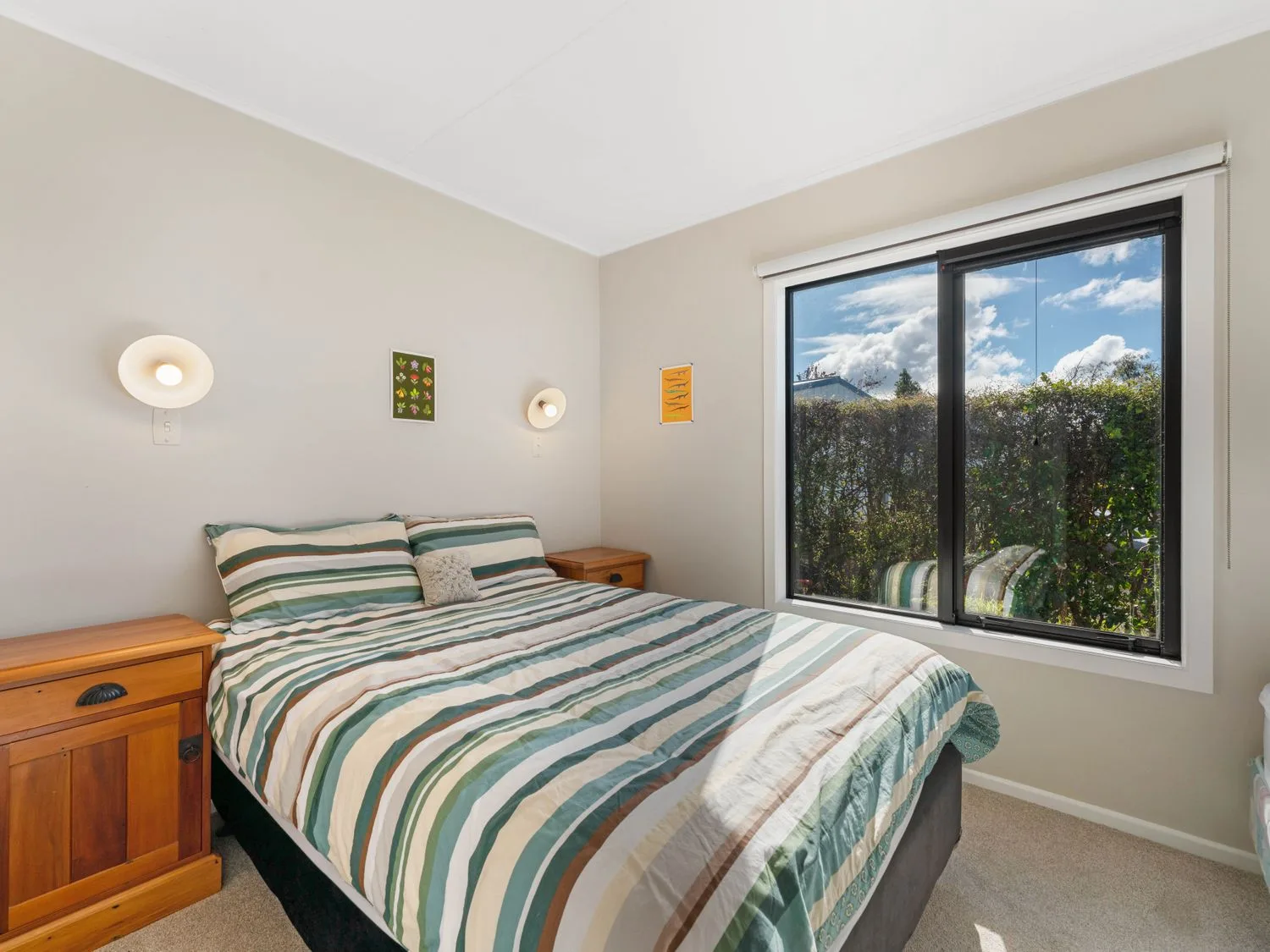 Un dormitorio con una cama a rayas y una gran ventana con vistas a la vegetación.