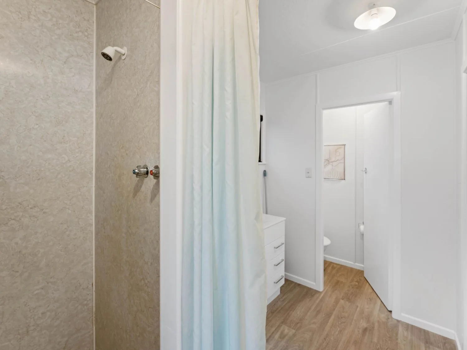 Un baño con una ducha con cortina y una puerta.