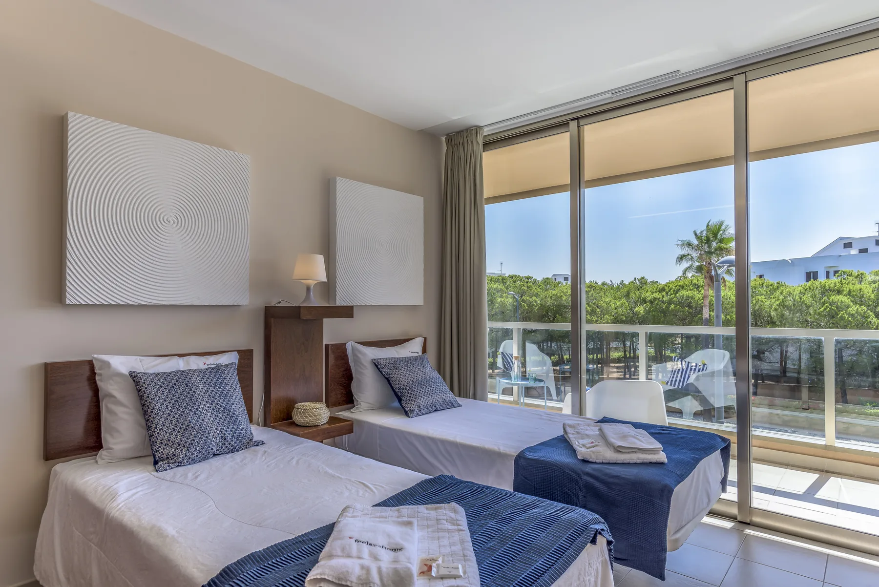 Un dormitorio con dos camas junto a grandes puertas correderas de cristal que dan a un balcón.