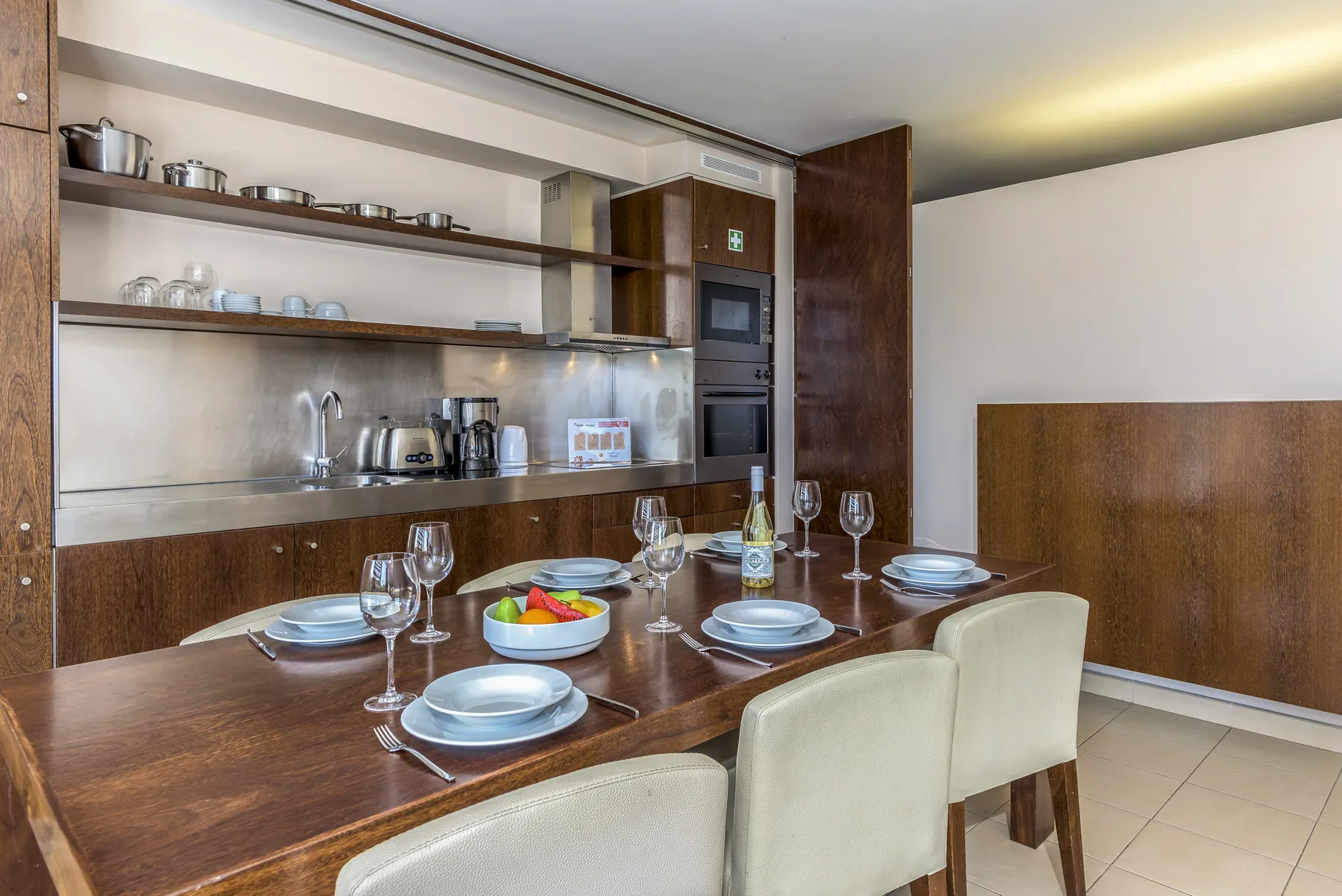 Un comedor con la mesa puesta está junto a una cocina abierta.
