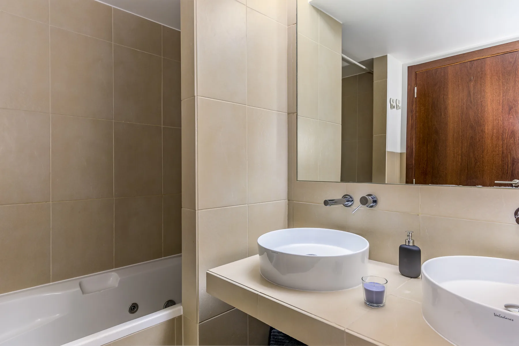 Un baño con bañera y un tocador con dos lavabos.