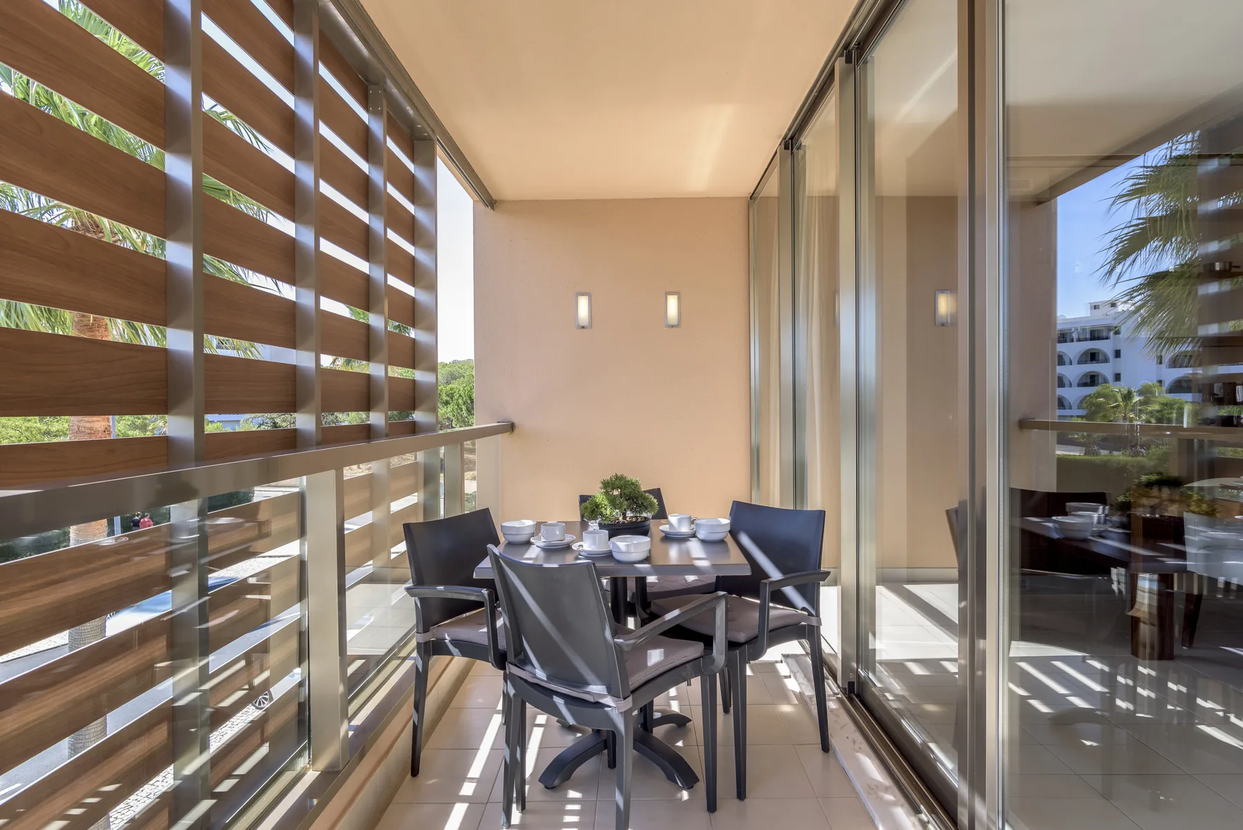 Comedor con mesa y sillas junto a puertas de vidrio y paneles de listones.
