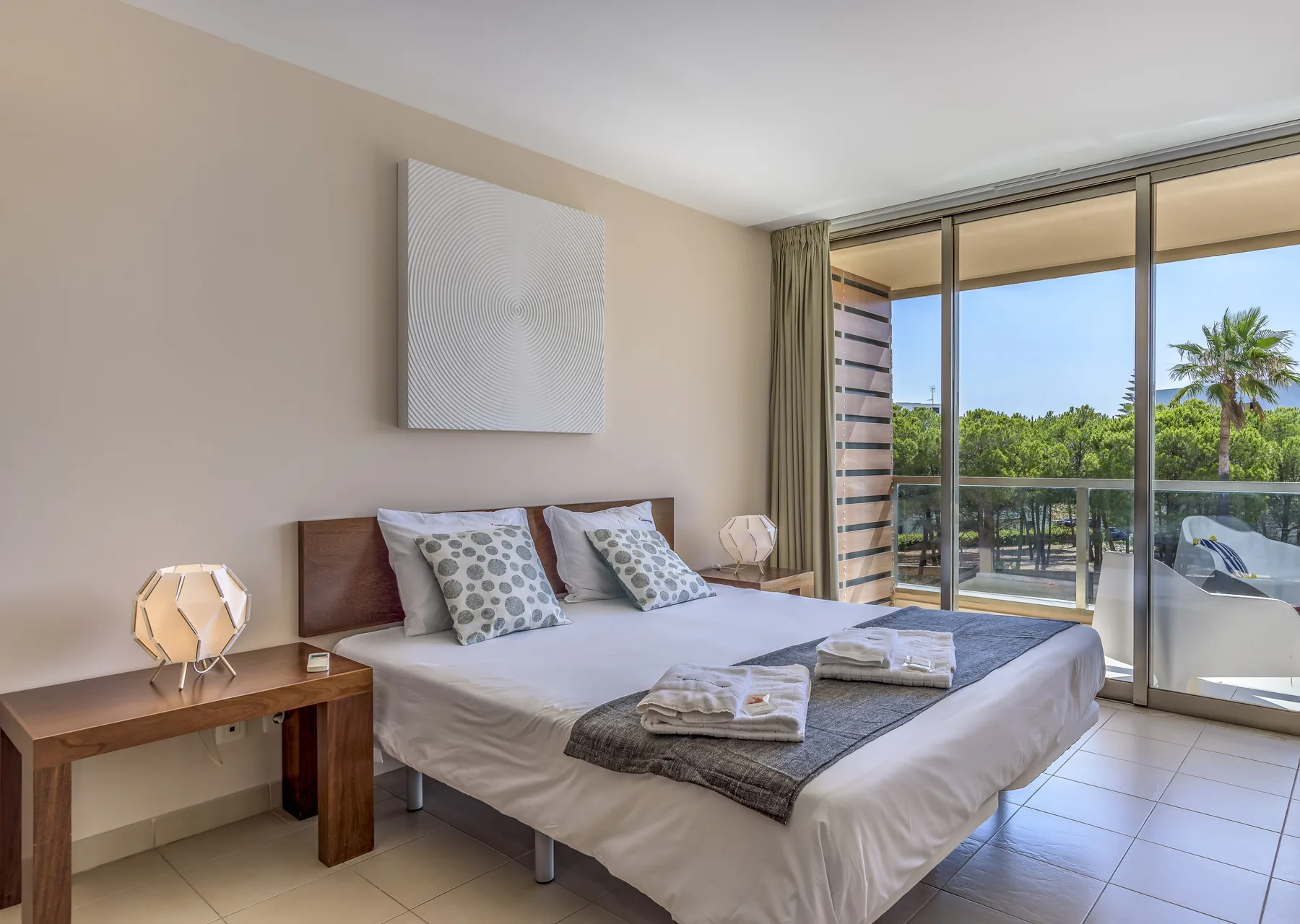 Un dormitorio con una cama junto a grandes puertas corredizas de vidrio que dan a un balcón.