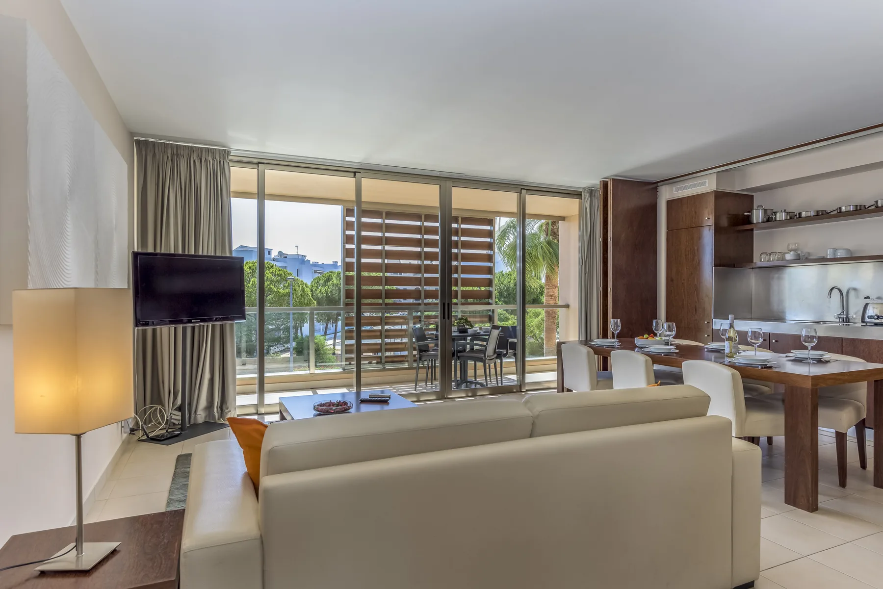 Sala de estar y comedor con asientos junto a grandes puertas de vidrio que dan a un balcón.