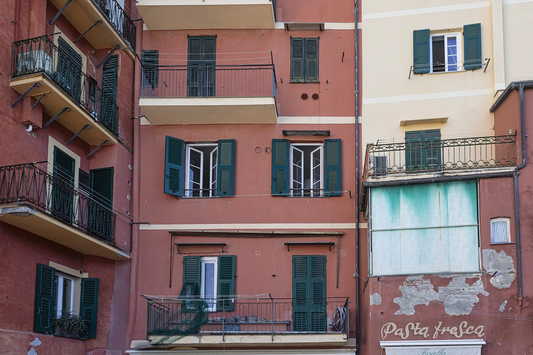 A row of colorful apartment facades with balconies and shuttered windows.