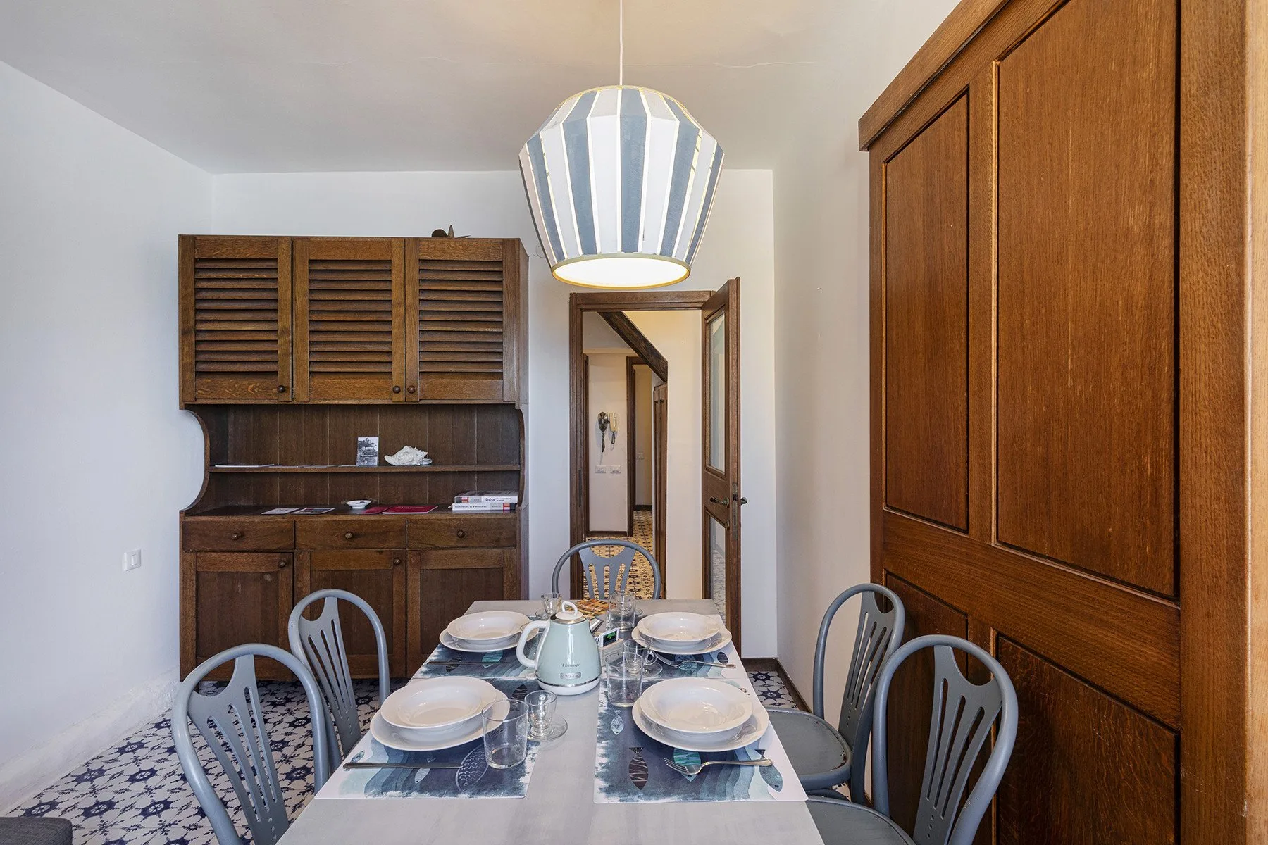 A dining area with a table set with dishes and wooden cabinets.