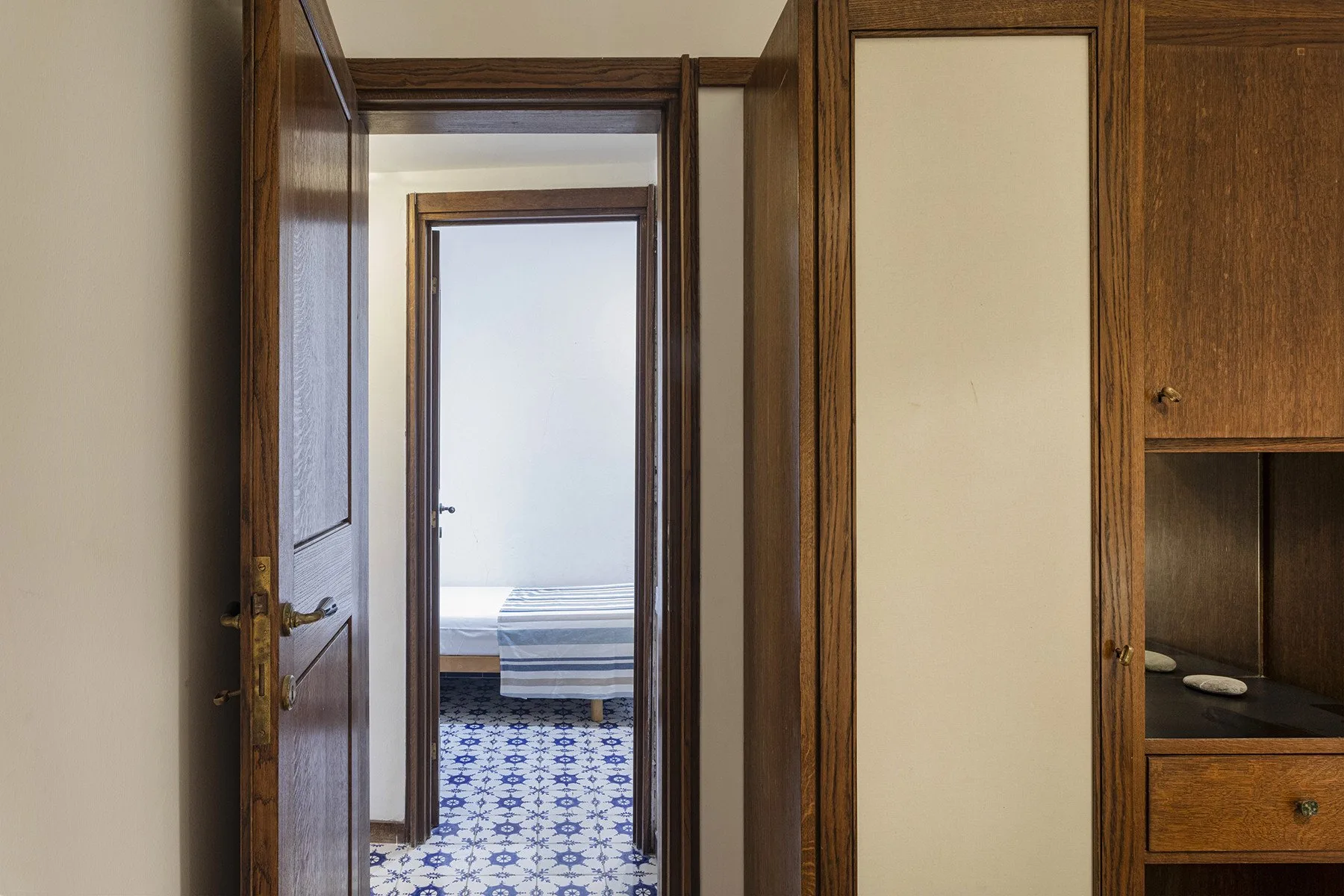 A hallway with open wooden doors and a room visible at the end.