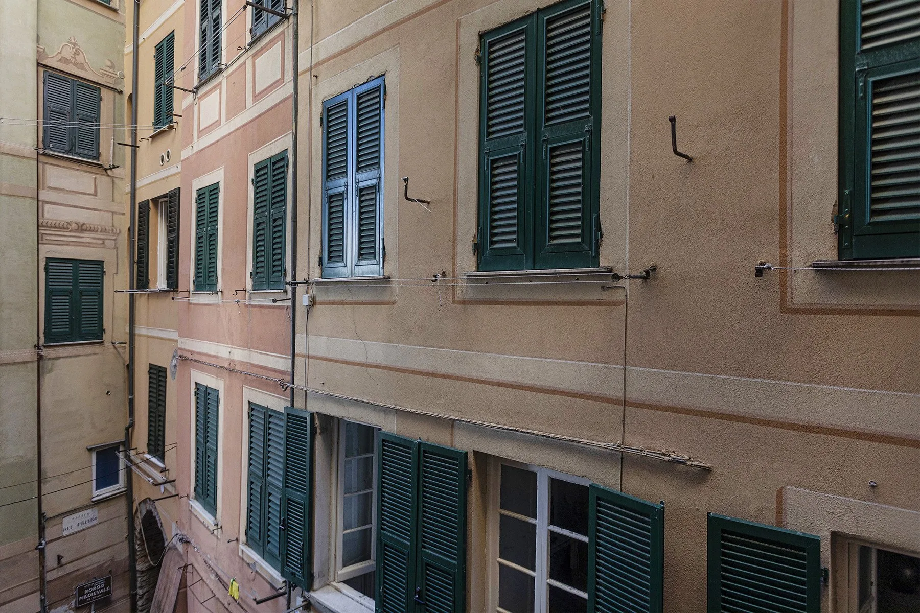 Exterior view of closely spaced building facades with shuttered windows.