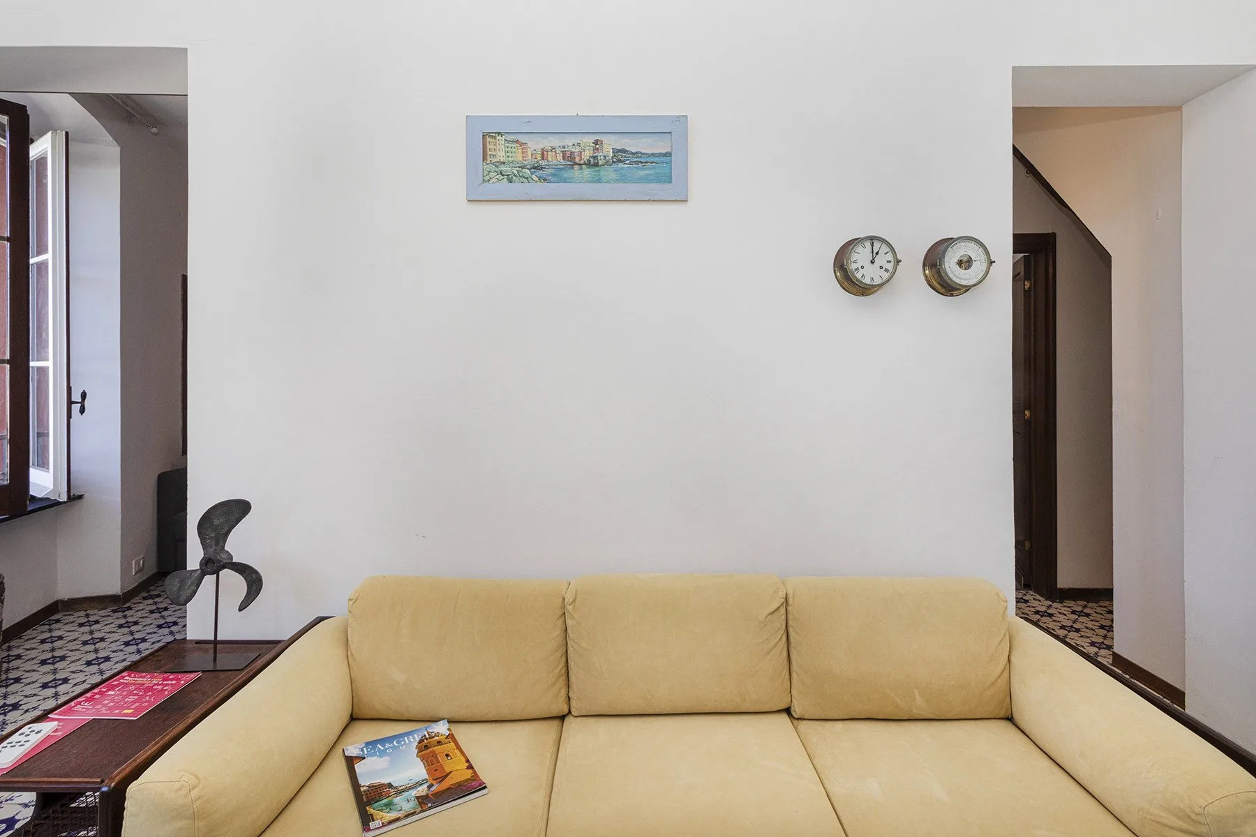 A living room with pale yellow seating and framed wall art.
