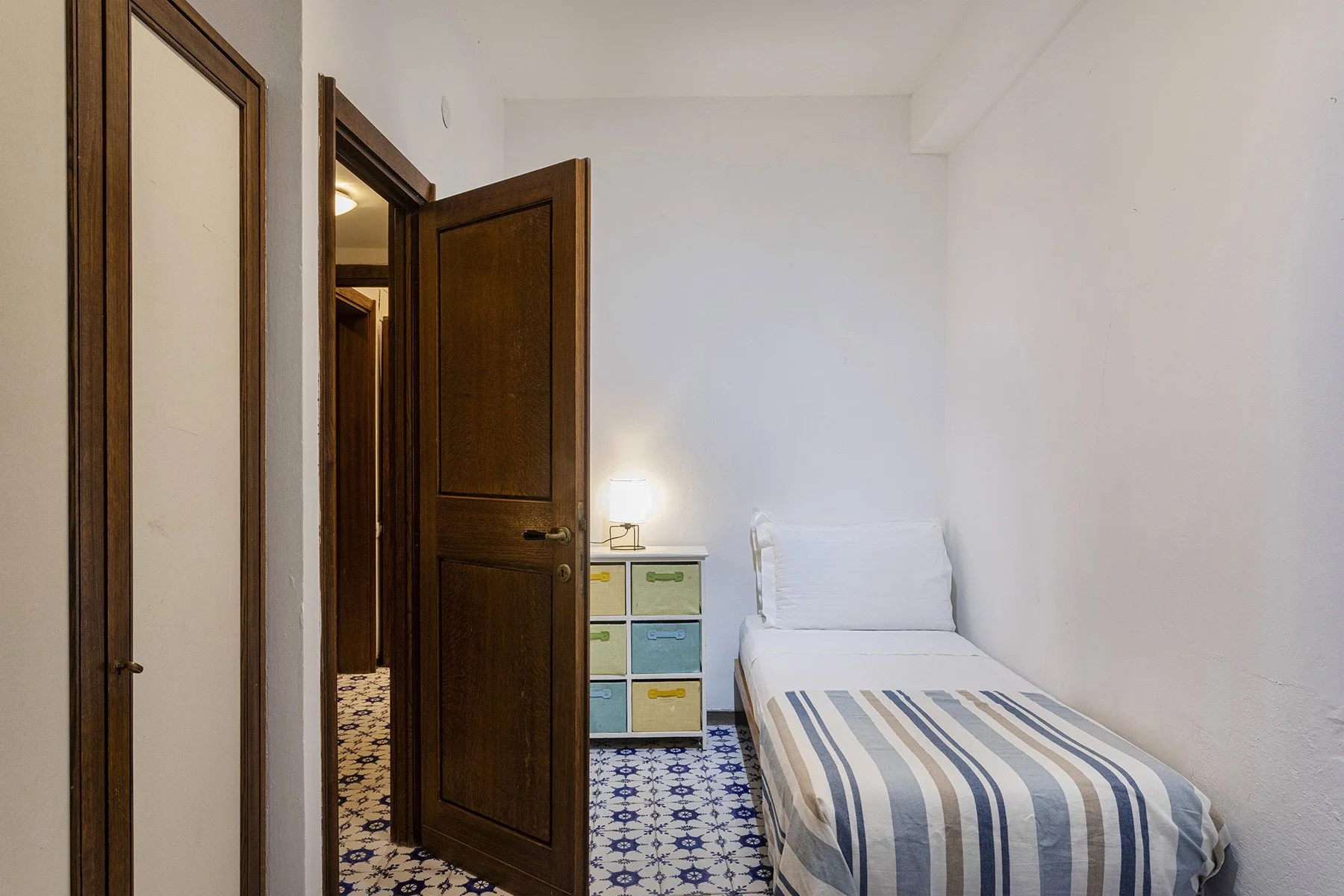 A small bedroom with a single bed and an open wooden door.