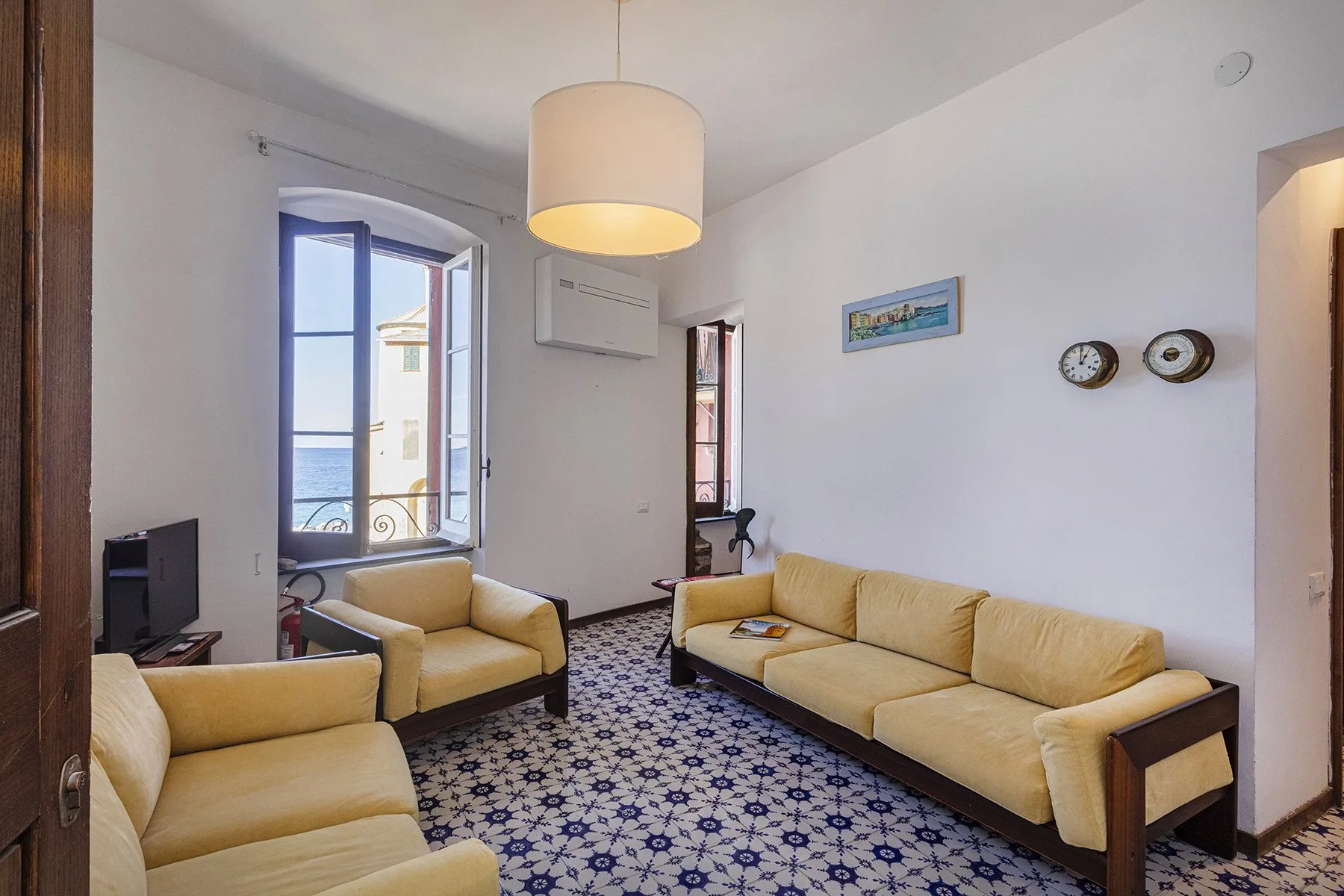 A living room with pale seating arranged around a patterned floor.