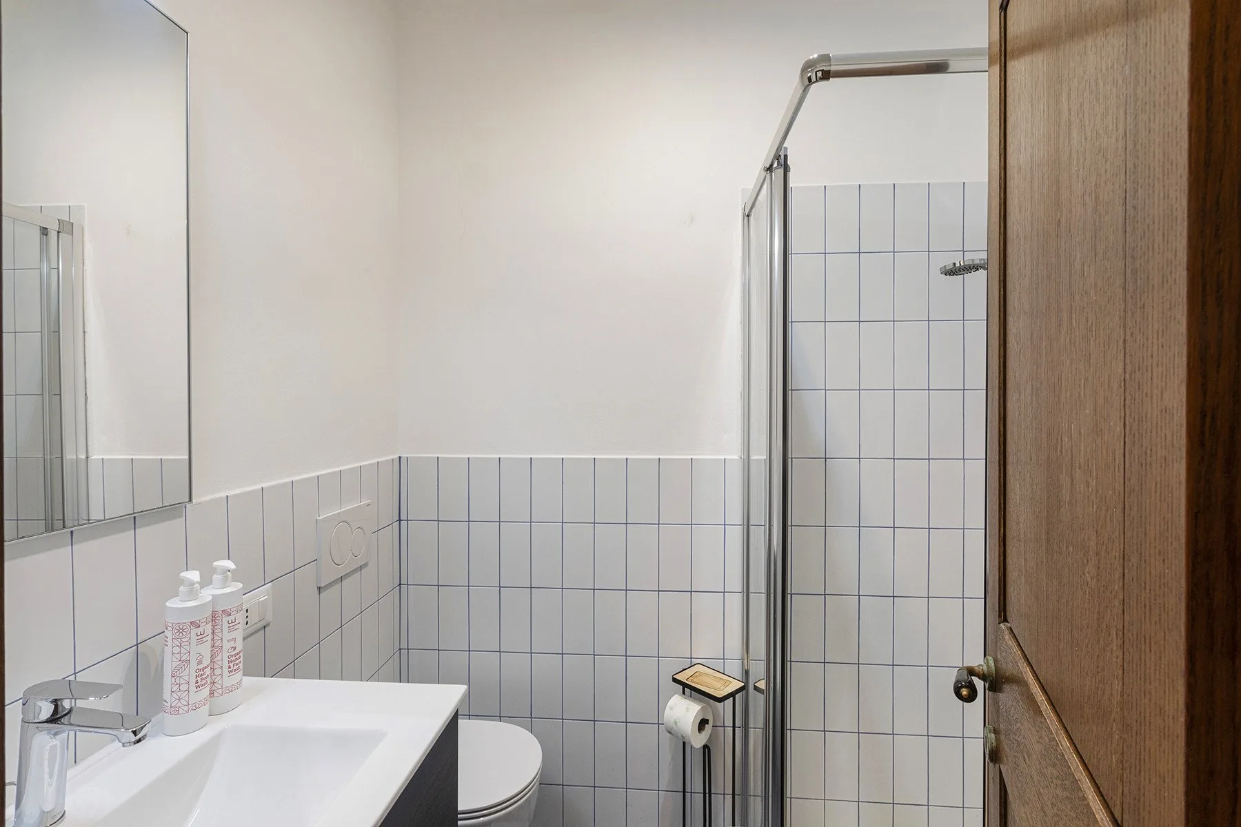 A bathroom with a sink, toilet, and tiled shower area.