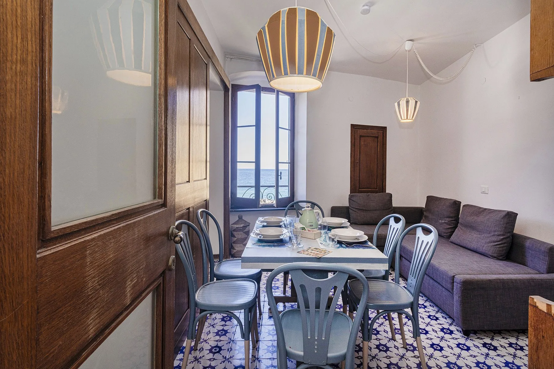 A dining area with a set table beside a seating area and tall windows.