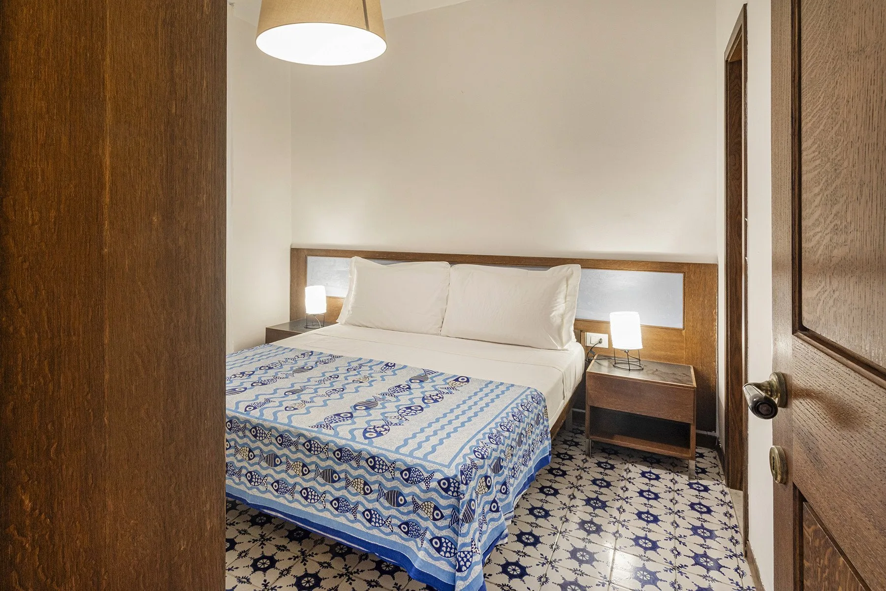 A bedroom with a bed covered by patterned bedding and bedside tables.