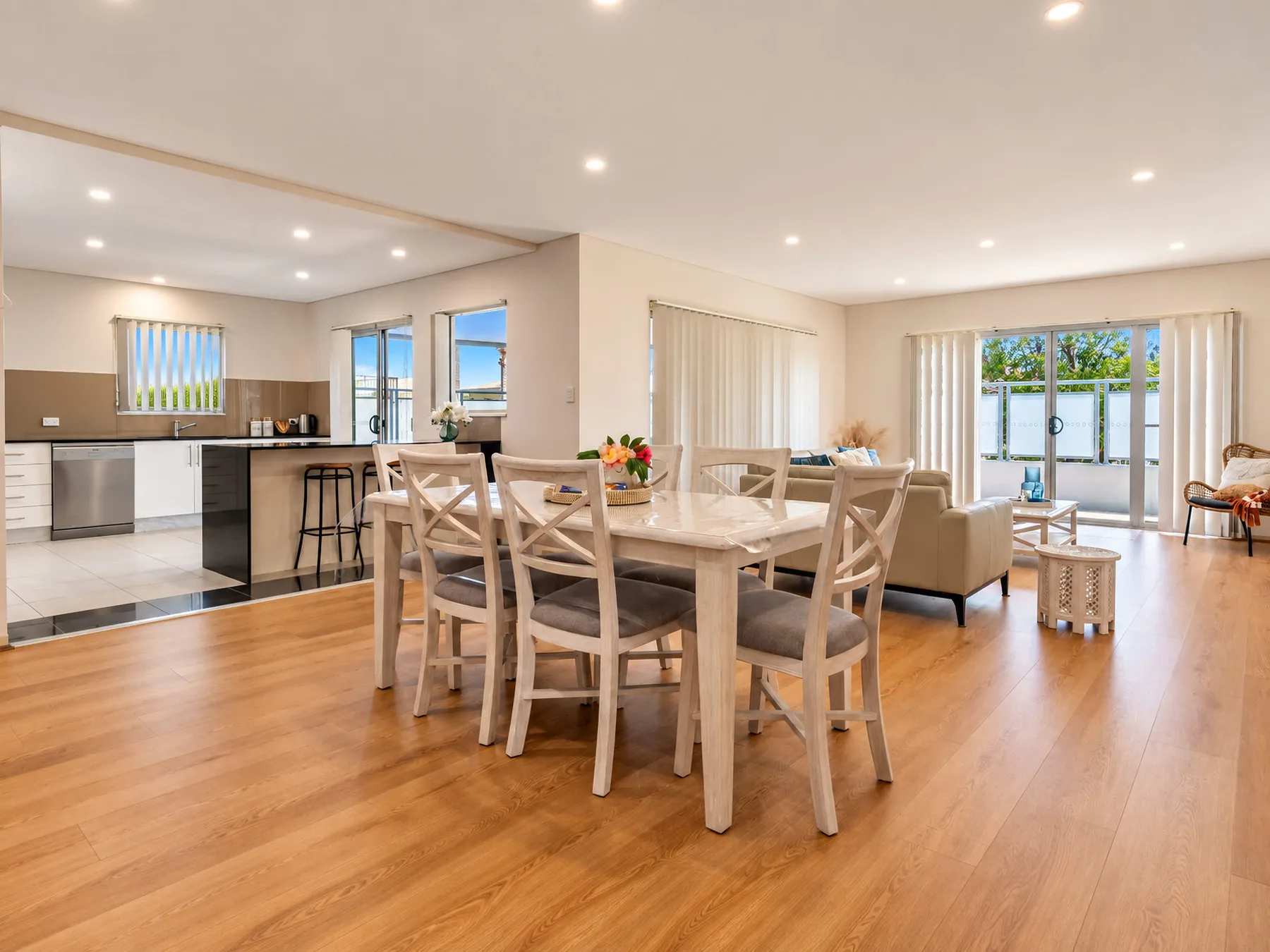 An open-plan dining and living area with a kitchen and sliding glass doors.