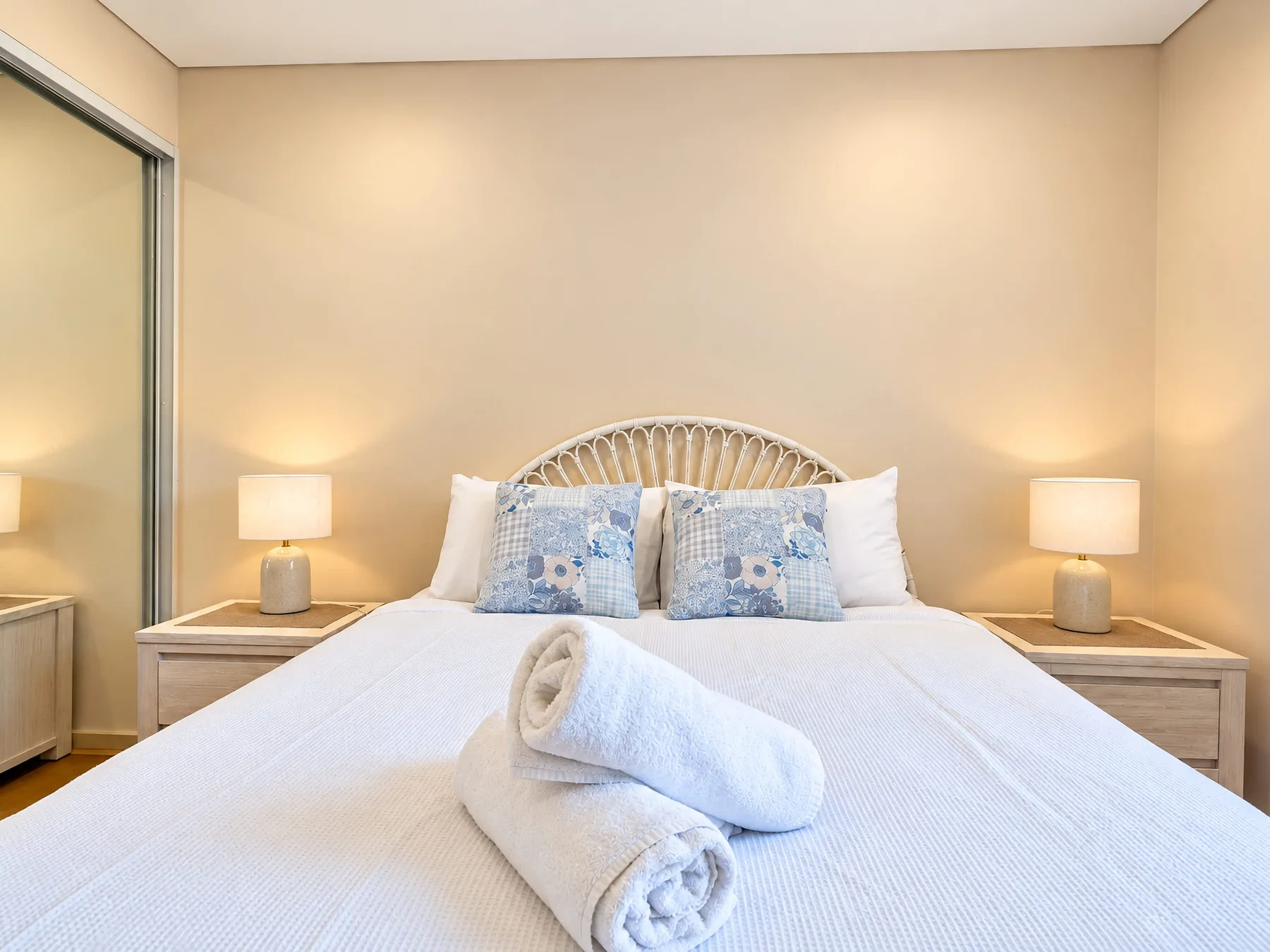 A bedroom with a neatly made bed, patterned pillows, and matching bedside lamps.