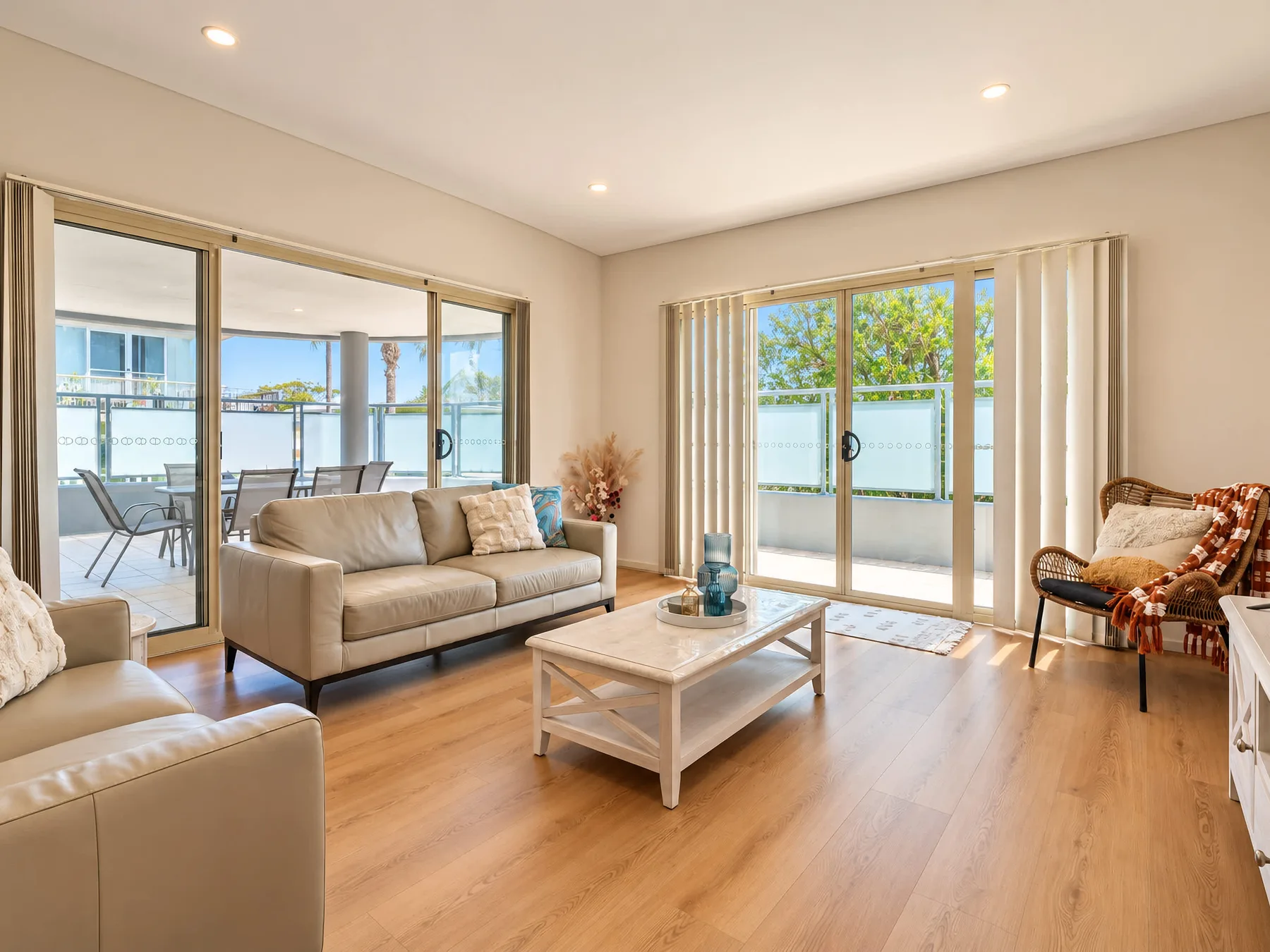 A bright living room with seating, a coffee table, and large glass doors.