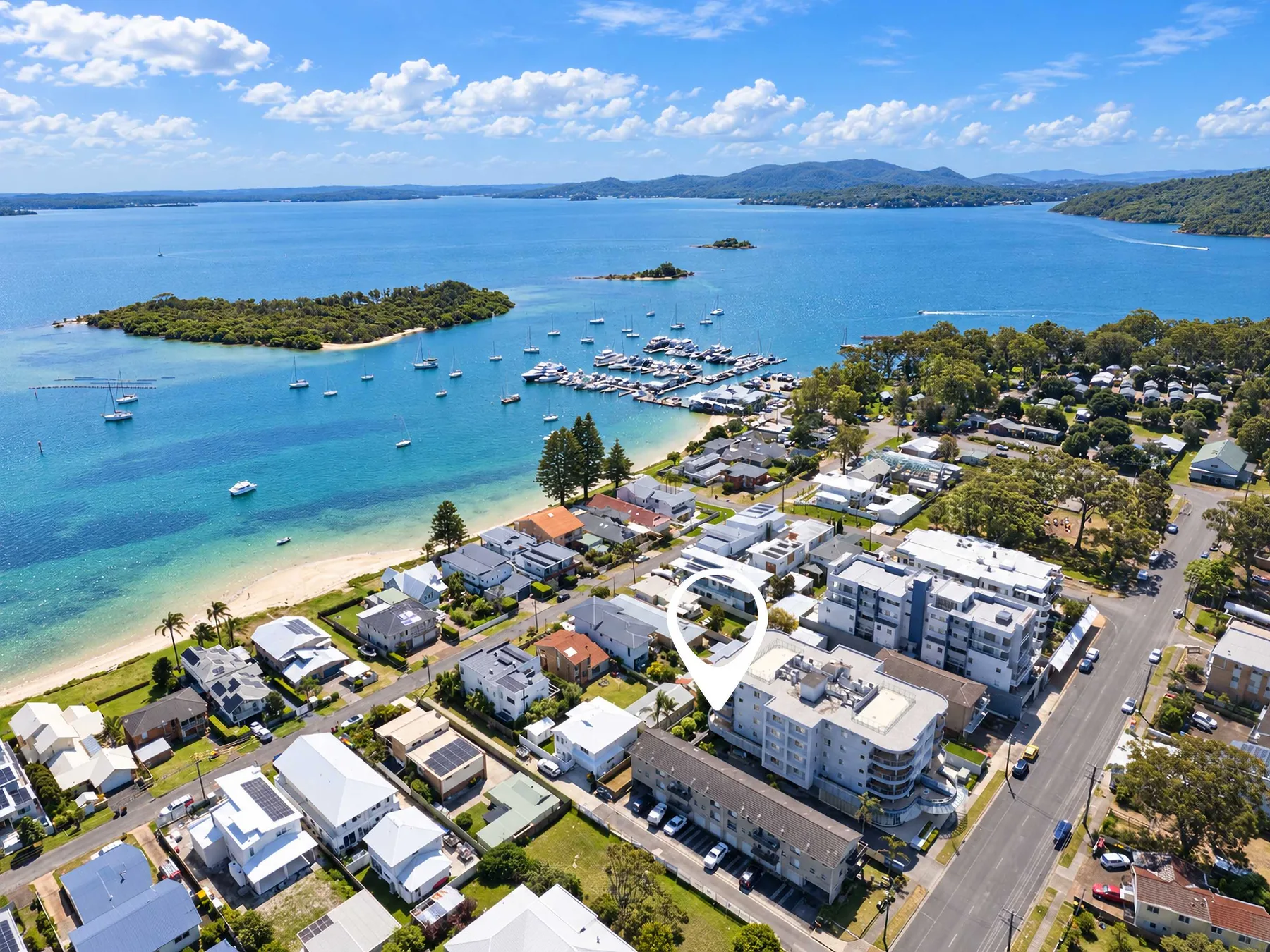 Aerial view of a coastal neighborhood beside a bay with boats and a marina.