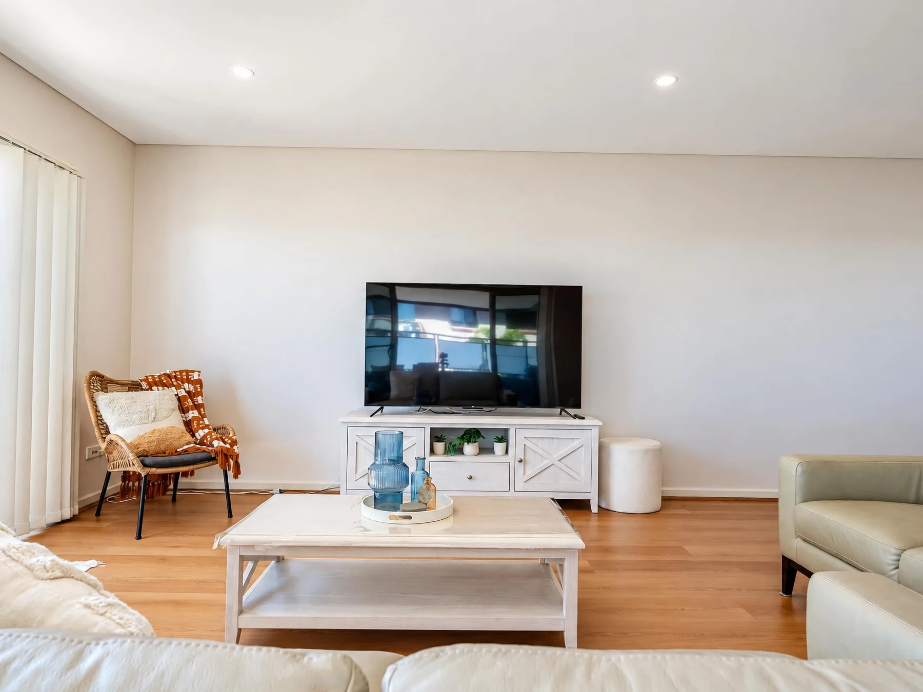 A bright living room with a television and seating around a coffee table.