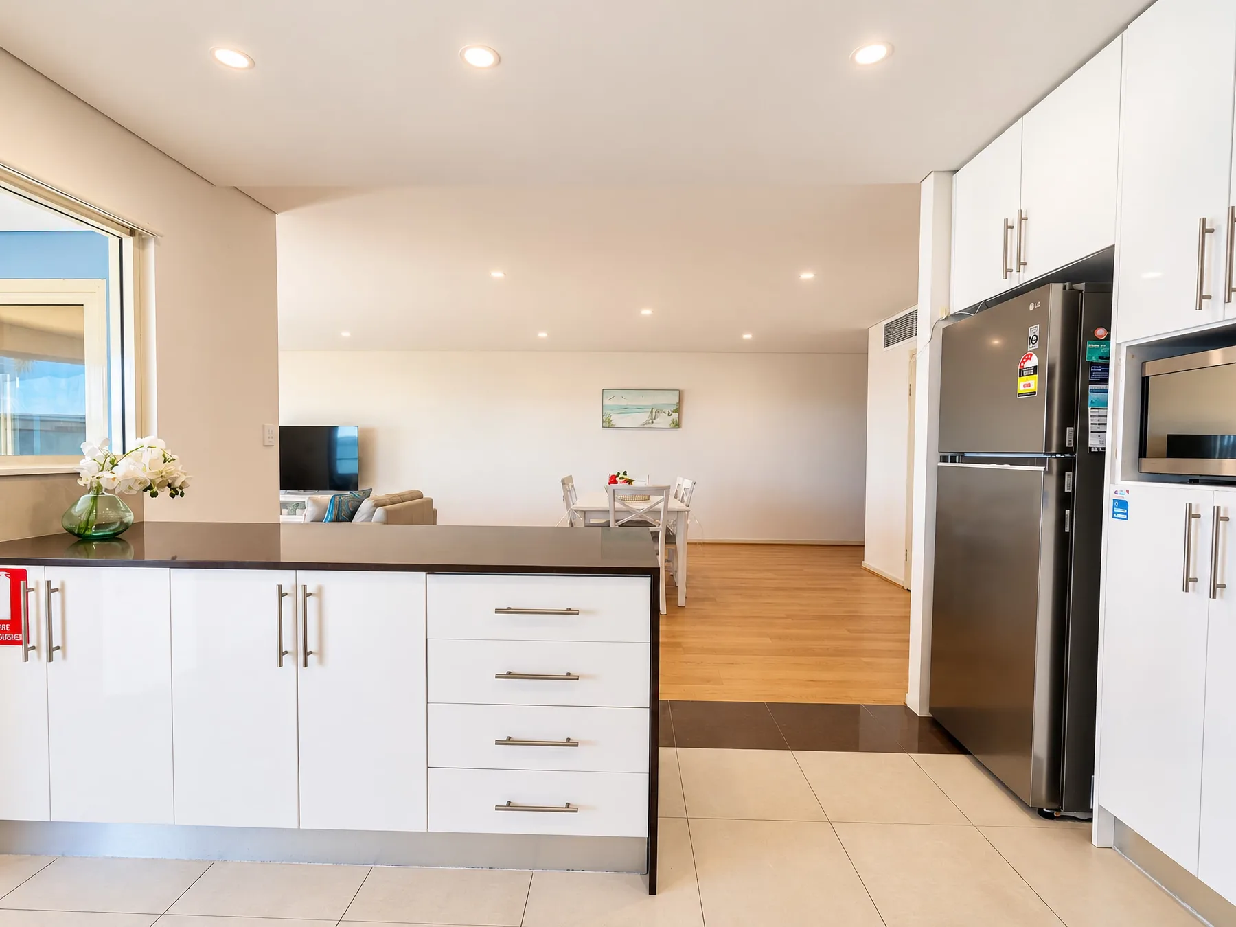 An open-plan kitchen and living area with a dining table and television.