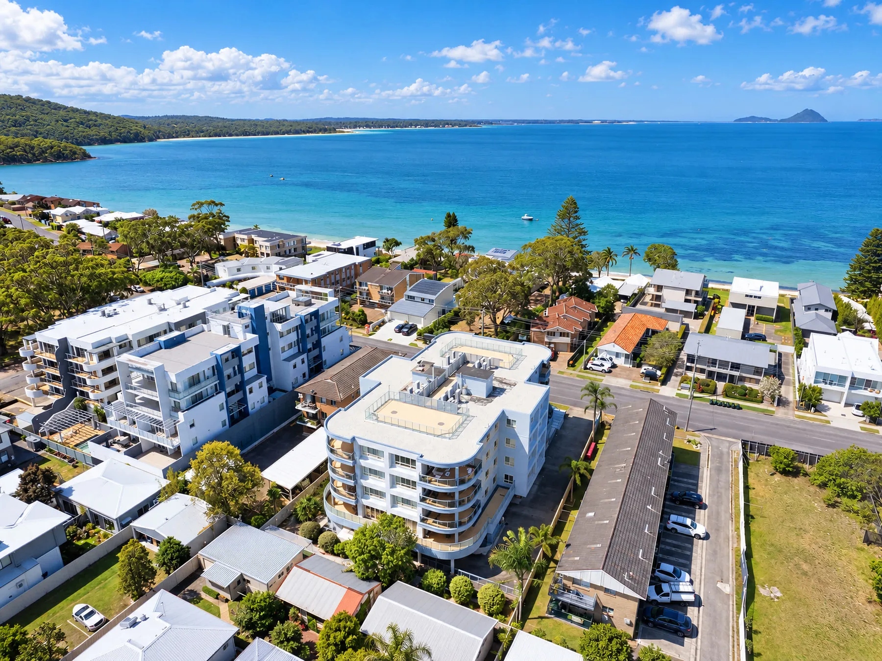 Aerial view of coastal buildings beside a turquoise bay and sandy shoreline.
