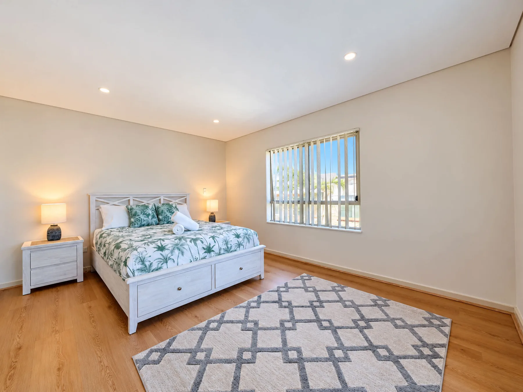 A bedroom with a bed, bedside tables, and a patterned rug.