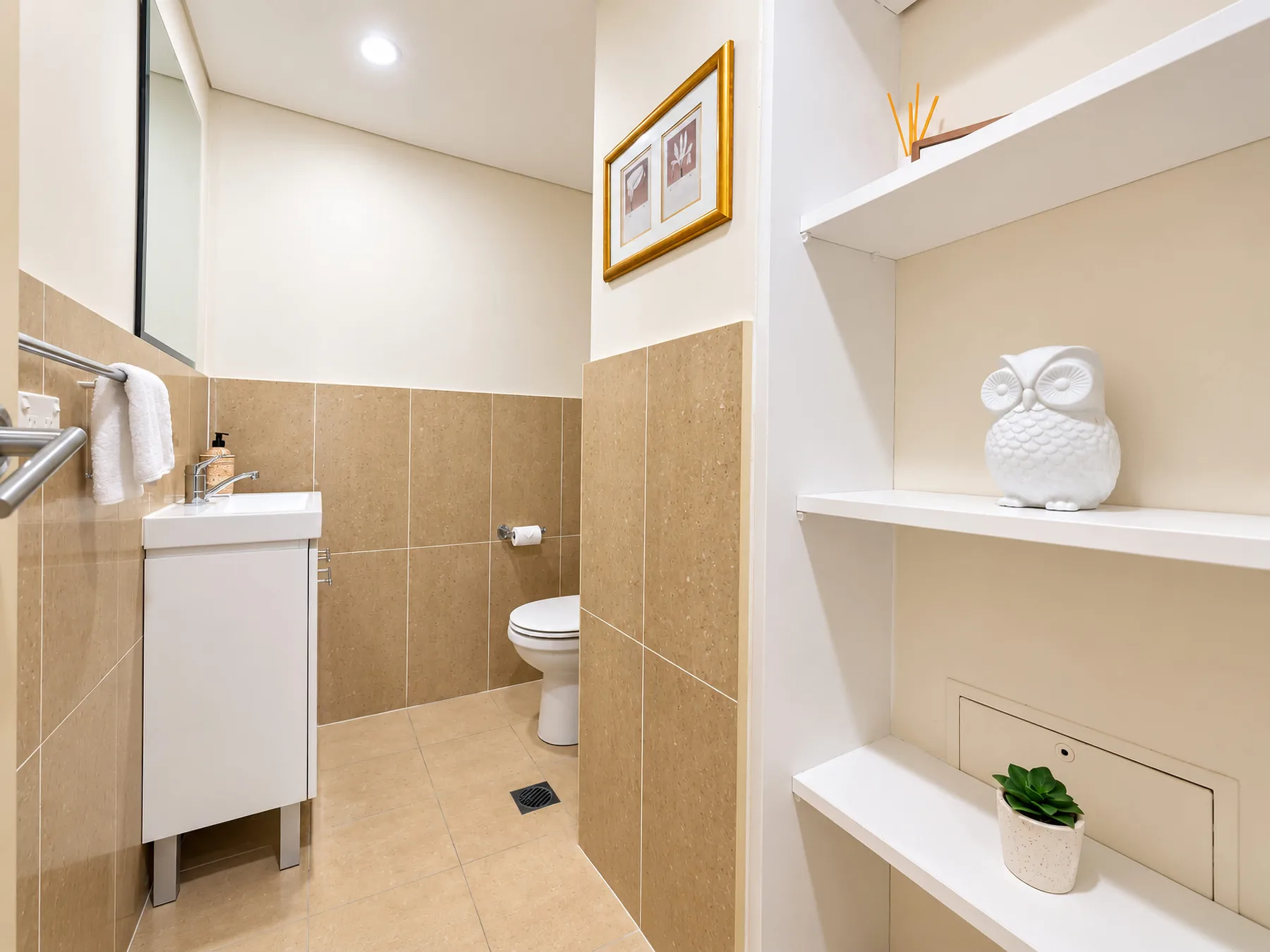 A bathroom with a sink and toilet beside built-in display shelves.