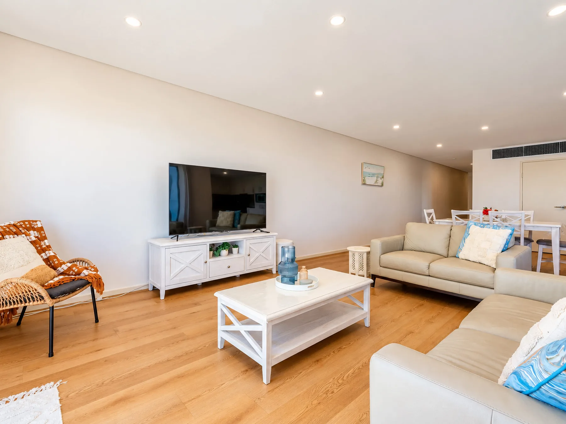 A living room with light seating, a television, and a coffee table.